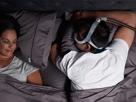 En patient, der bærer en ResMed AirFit N30i-nasalmaske, mens han sover på forsiden.