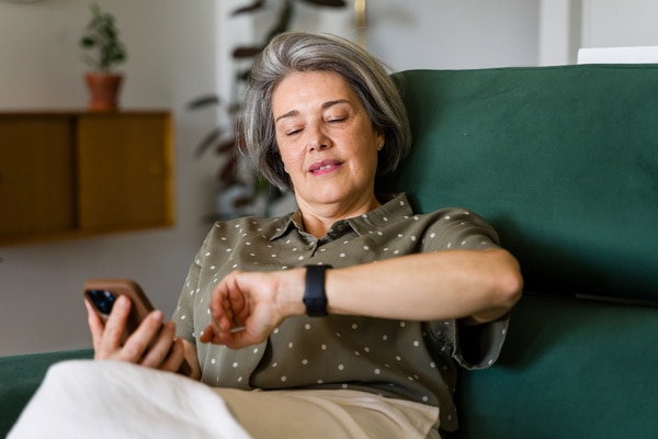  Kvinde, der kigger på sit Apple Watch og sin telefon